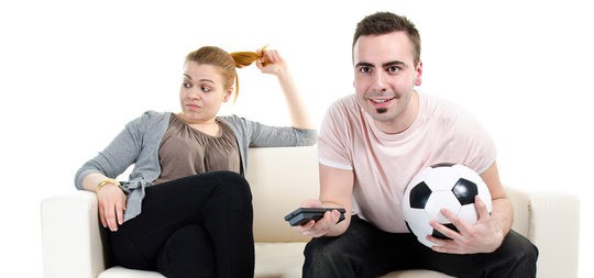 Chica aburrida mientras su novio ve un partido de fútbol